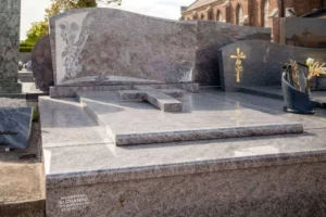 Monument funéraire en granit rose veiné surmonté d'une croix sculptée en relief