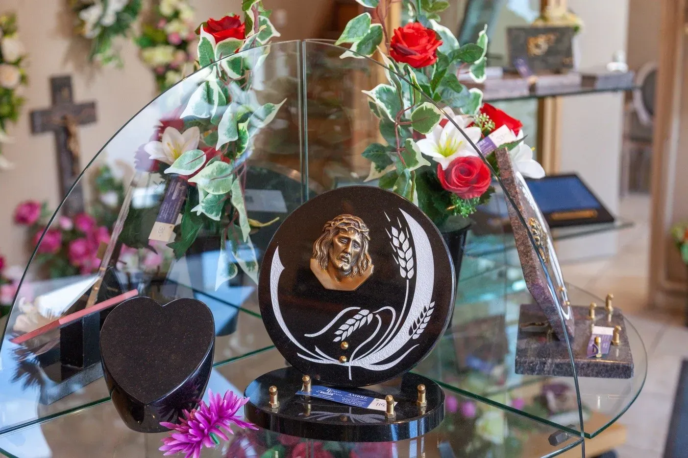 Plaque funéraire en granit noir gravée d'un Christ et d'épis de blé sous vitrine